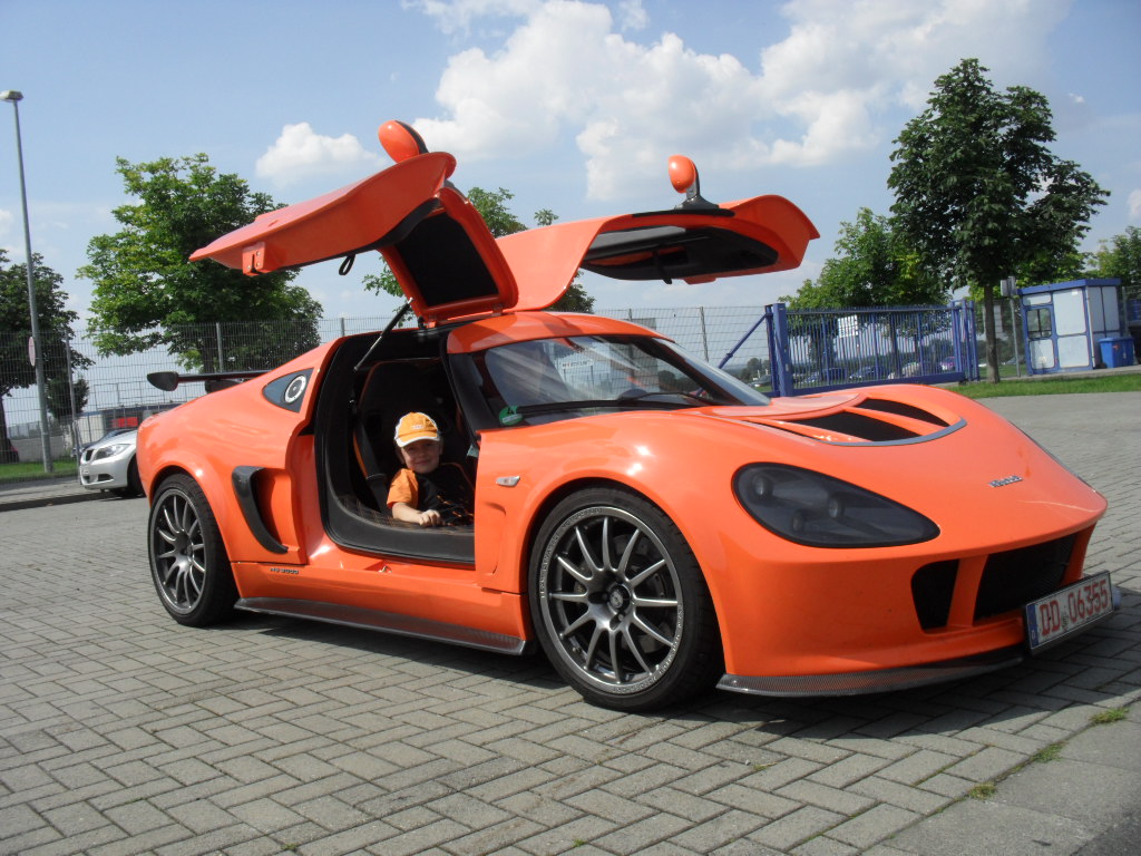 Orangener MELKUS RS2000 mit geöffneten Flügeltüren, darin sitzt ein kleiner Junge mit orangener Schirmmütze